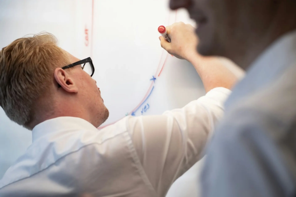 Un homme ecrivant sur un tableau blanc
